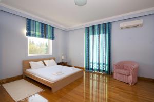 una camera con un letto bianco e una sedia rosa di Supreme and Classy Pool Residence a Paianía Altre 15 foto