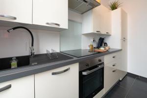 een keuken met witte kasten en een zwarte wastafel bij Santorin Îlot de Merville - Centre in Lorient