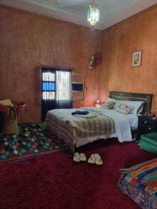 a bedroom with a bed and a pair of shoes at Dar Mayssa Rose in Zawyat
