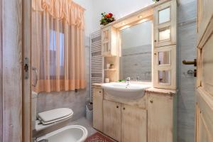 Un baño con lavabo, inodoro y espejo. en Viviana's Holiday Home, en Trinità dʼAgultu