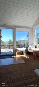 a living room with a bed and a table in front of windows at Cozy cabin in the Gilja paradise in Frafjord