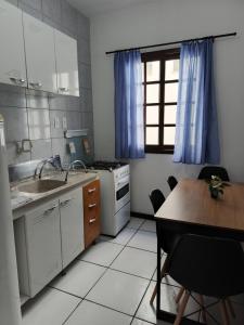 a kitchen with a table and a sink and a stove at Residencial DO MAR in Bombinhas +13 photos