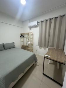 ein Schlafzimmer mit einem Bett und einem Tisch und einem Fenster in der Unterkunft Aconchego apartamento com garagem 5 min da COP30 in Belém