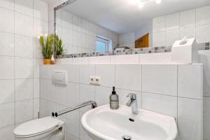 a white bathroom with a sink and a toilet at Ferienwohnung Bruttel in Gaienhofen +18 photos