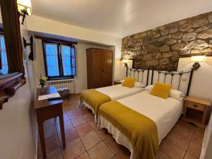 - 2 lits dans une chambre avec un mur en pierre dans l'établissement Posada la Estela de Barros, à Los Corrales de Buelna