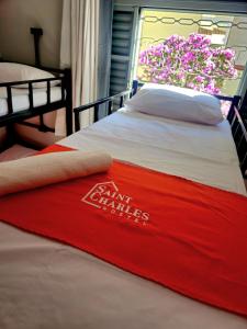 una manta roja en una cama con ventana en Saint Charles Hostel, en São Carlos