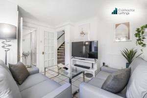 Una sala de estar blanca con un sofá y un televisor. en 4 Bedroom Elegant House Near Peterborough City Center with Free Parking - Angus Suites by Contractor Lettings, en Peterborough