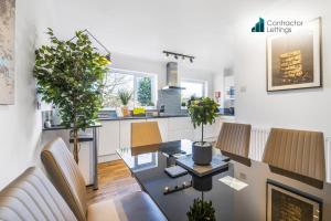 Una sala de estar con mesa y sillas y una cocina. en 4 Bedroom Elegant House Near Peterborough City Center with Free Parking - Angus Suites by Contractor Lettings, en Peterborough