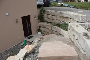 a stone retaining wall next to a building with a door at Ferienwohnung Spielmann in Sauldorf +3 photos
