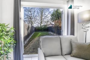 Una sala de estar con un sofá blanco y una ventana. en 4 Bedroom Elegant House Near Peterborough City Center with Free Parking - Angus Suites by Contractor Lettings, en Peterborough