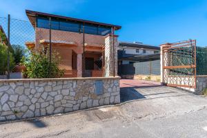 a building with a fence next to a stone wall at Casa Pina a due passi dal mare in Augusta