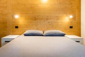a bed with two pillows in a room with wooden walls at Appartamenti Via Dell'Asilo in Isolaccia