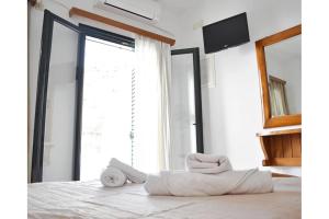 een slaapkamer met een wit bed en een spiegel bij Manolika Studio 4 in Kithnos