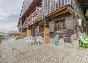 a wooden deck with a table and chairs in front of a house at Le Planay in Notre-Dame-de-Bellecombe
