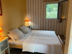 a bedroom with a bed with white sheets and a window at Eco Gîte in Payzac