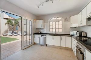 サンミゲル・デ・アボナにあるVilla Jacarandaのキッチン(白いキャビネット付)、パティオ(椅子付)