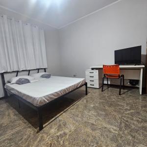 a bedroom with a bed and a desk and a computer at Saint Charles Hostel in São Carlos