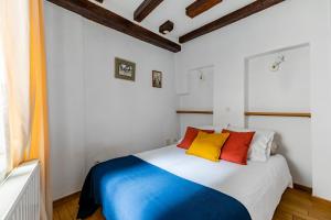 une chambre avec un lit avec des oreillers colorés dessus dans l'établissement Charmant et typique 2 pièces Place de la Cathédrale, à Strasbourg