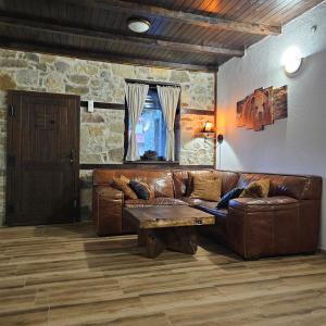 een woonkamer met een bruine leren bank en een tafel bij Къща за гости МЕЧА СТЪПКА in Gela +24 foto's