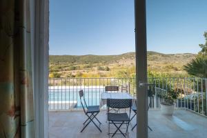 eine Terrasse mit Tisch und Stühlen auf einem Balkon in der Unterkunft Appartement N°1 - Piscine Partagée in Lagorce