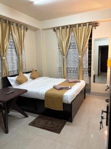 a bedroom with a bed and a table and windows at The urban rest in Shillong
