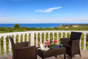 a balcony with two chairs and a table with flowers at Zante View villa Odysseus in Plános