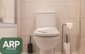 a bathroom with a white toilet with towels on it at Green Park House, Private Garage and Parking in Coventry