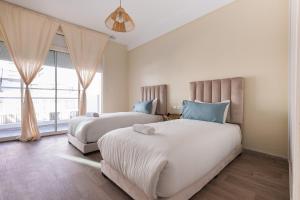 a bedroom with two beds and a large window at Élégant 2BR au cœur de Hassan by MERAT HOME in Rabat