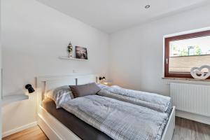 Un dormitorio blanco con una cama con ventana. en Fe Wo Koll, en Weddingstedt