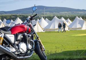 a motorcycle parked in front of a field with tents at Nine Yards Bell Tents at the TT - Castletown in Castletown +4 photos