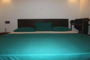 a large bed with green sheets and blue pillows at Natura in Dickwella