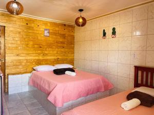 a bedroom with a bed with pink sheets and wooden walls at Pousada Maria Bonita Abreu e Lima in Maricota +35 photos