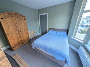a bedroom with a bed and a wooden cabinet at Quiet Private Room in Prime Location in Derry Londonderry