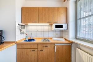 a small kitchen with wooden cabinets and a microwave at Fewo Brünnstein - Nr 61 Pool, Sauna in Oberaudorf