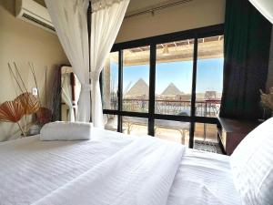 a bedroom with a large bed and a large window at Cozy vintage duplex Khan -khan luxe residence pyramids view in Cairo