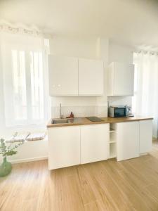 a kitchen with white cabinets and a wooden floor at Mourillon proche plages in Toulon