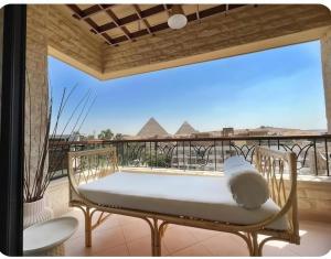 a bench on a balcony with a view of the pyramids at Cozy vintage duplex Khan -khan luxe residence pyramids view in Cairo