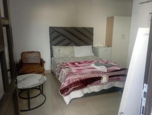 een kleine slaapkamer met een bed en een stoel bij The trout Lodge in Kaapstad