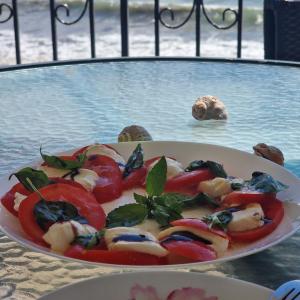 a plate of food with tomatoes and basil on a table at Charming Studio at the Seaside in Aheloy