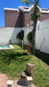 a chair sitting next to a tree in a yard at Alojamiento céntrico en San Nicolás in San Nicolás de los Arroyos