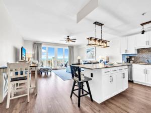 eine Küche und ein Wohnzimmer mit weißen Schränken und einem Tisch in der Unterkunft Laketown Wharf 1213 in Panama City Beach