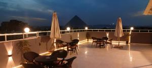 a balcony with tables and chairs and umbrellas at night at Phoenix Pyramids View Inn in Cairo