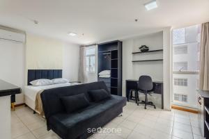 a bedroom with a bed and a desk and a couch at Lindos Estúdios em Condomínio c/ Piscina - Águas Claras - MADB in Águas Claras +22 photos