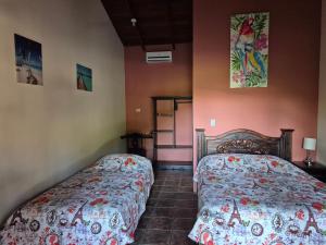 two beds in a room with pink walls at Hotel El Paraiso Escondido - Costa Rica in Jacó