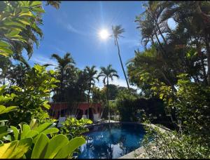 a pool in a garden with palm trees at Hotel El Paraiso Escondido - Costa Rica in Jacó