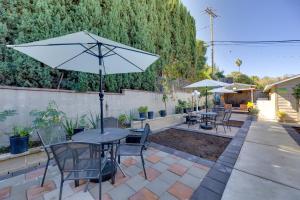 eine Terrasse mit Tischen und Stühlen und einem Sonnenschirm in der Unterkunft Walk to Main St! Pet-Friendly Alhambra Studio in South Pasadena