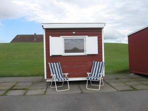 deux chaises assises devant une petite maison dans l'établissement Ferienhaus Stie Tinningstedt, à Tinningstedt