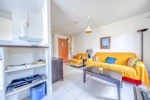 Una sala de estar con un sofá amarillo y una mesa. en Studio avec piscine - proche plage, en Soulac-sur-Mer