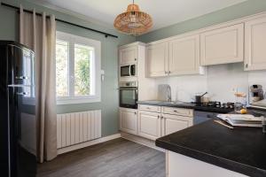 a kitchen with white cabinets and a black counter top at Le Cocon des Allamandières in Chonas-lʼAmballan +12 photos