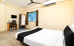 a bedroom with a bed and a desk with a window at Hotel O Profulla Devi Guest House in Jojera
